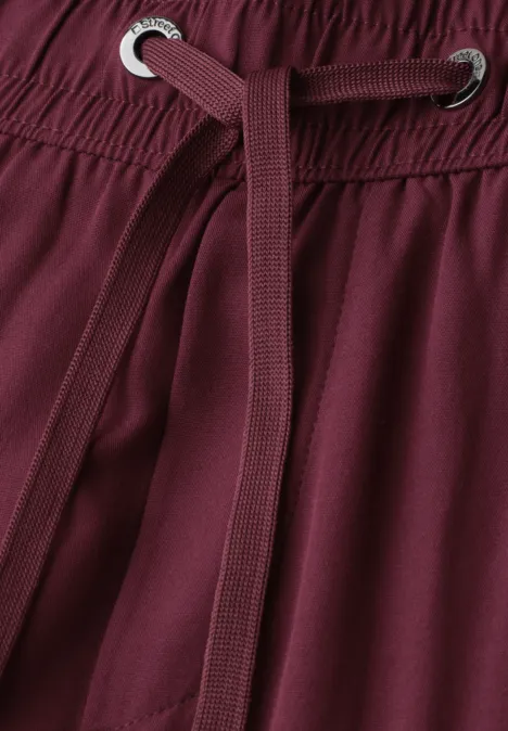 Nahaufnahme einer burgunderfarbenen Hose mit Tunnelzug und Elastikbund.