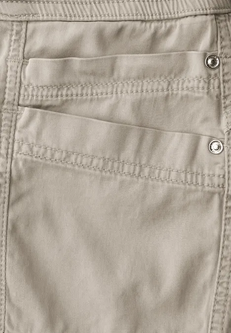 Cargo Joggpants buff grey Nahaufnahme einer beigen Hose mit mehreren Taschen und sichtbaren Nähten sowie Druckknöpfen.