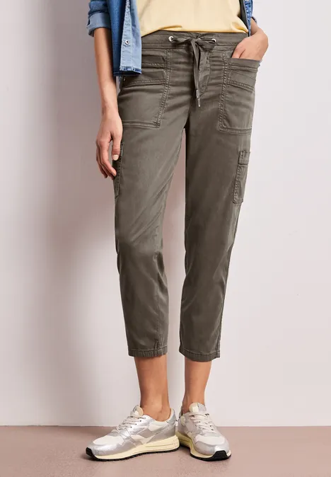 Damen-Cargo-Hose in Khaki mit Kordelzug, aufgekrempelt, kombiniert mit hellen Sneakern.
