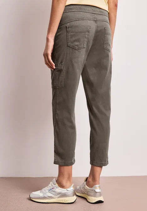 Rückenansicht einer Person in olivgrüner Cargohose und Sneakers.