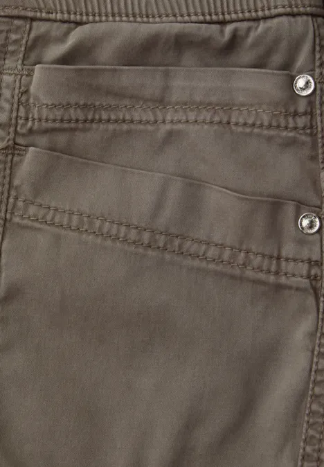 Nahaufnahme einer braunen Hose mit dekorativen Nähten und silbernen Nieten.