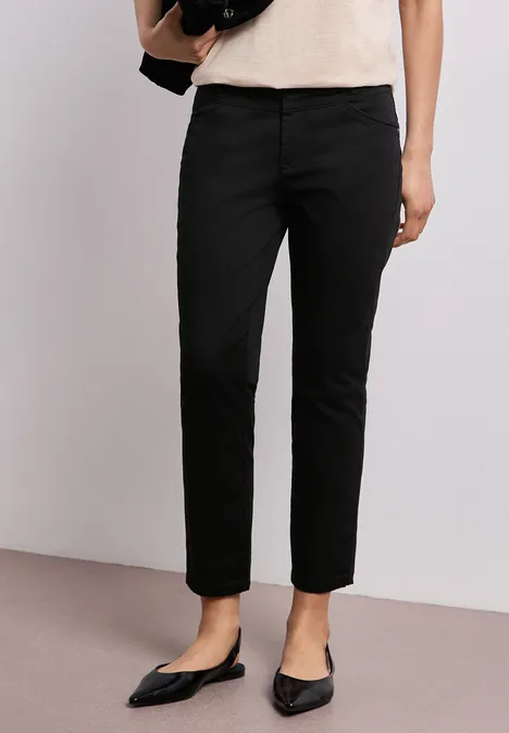 Schwarze, gerade geschnittene Damenhose kombiniert mit spitzen Ballerinas und einem hellen Oberteil