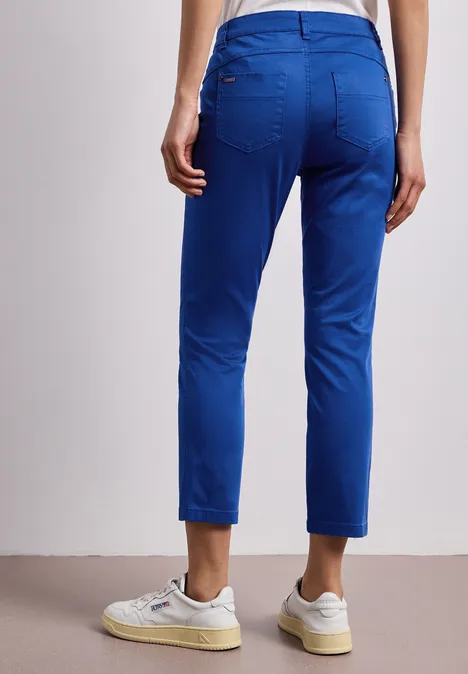 7/8 Slim Legs broek in satijnlook amparo blue Een persoon van achteren draagt een blauwe broek en witte sneakers.