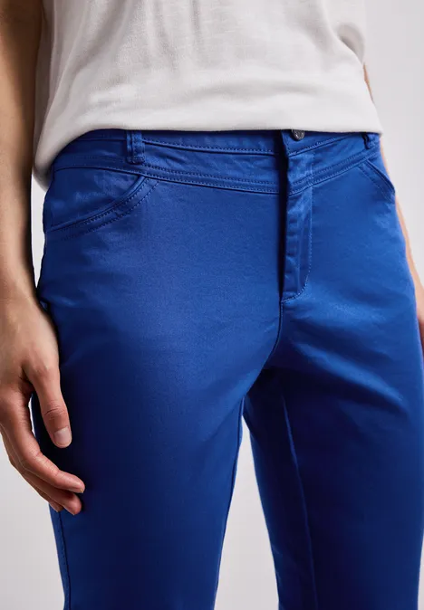 7/8 Slim Legs broek in satijnlook amparo blue Een persoon draagt een felblauwe chino en een wit shirt, alleen het onderste deel van de romp is zichtbaar.