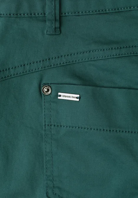 Grüner Hosen-Taschenbereich mit Ziernaht, Metallknopf und kleinem Etikett.