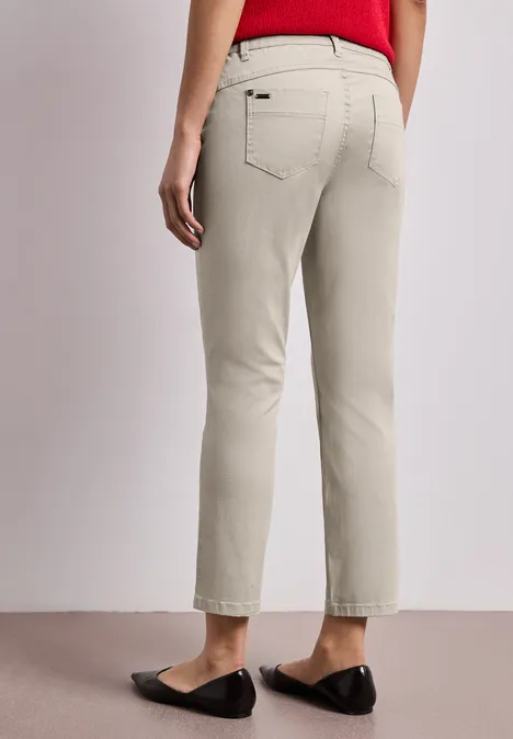7/8 Slim Legs broek in satijnlook cobble stone Achteraanzicht van persoon in lichtbeige, rechte broek met achterzak en zwarte platte schoenen.