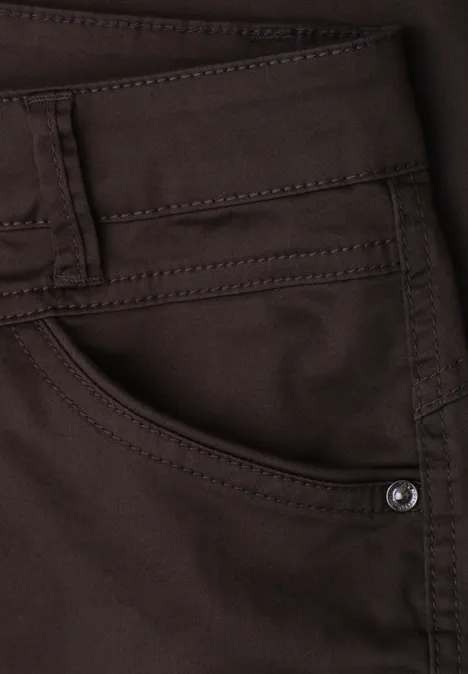 7/8 Slim Legs broek in satijnlook deep earth Close-up van een bruine spijkerbroek met zak, riemlussen en klinknagel.