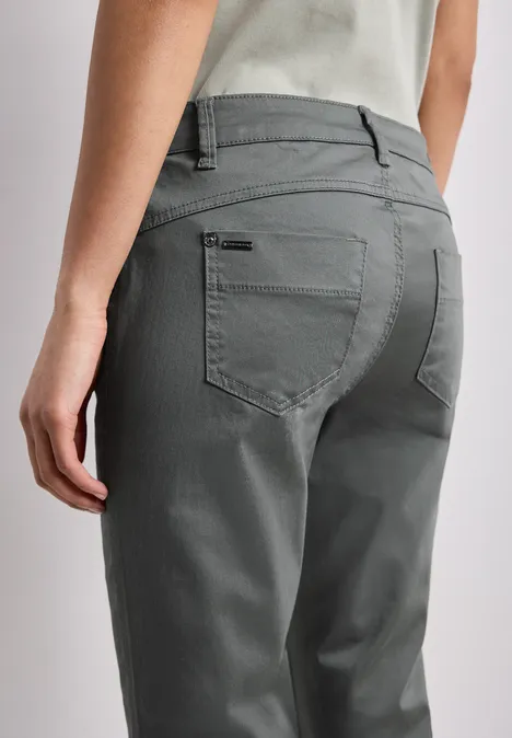 7/8 Slim Legs broek in satijnlook cilantro green Achteraanzicht van een persoon met een grijze broek en een licht shirt