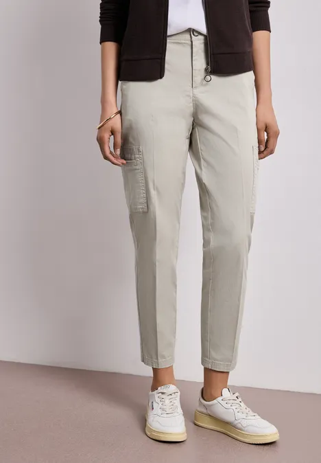 Beige Cargohose mit aufgesetzten Taschen, kombiniert mit weißen Sneakern.