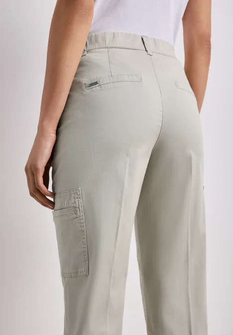 Chino's met Slim Legs en cargo-stijl zakken cobble stone Achteraanzicht van een persoon in lichtgrijze cargobroek met een zijzak op de dij.