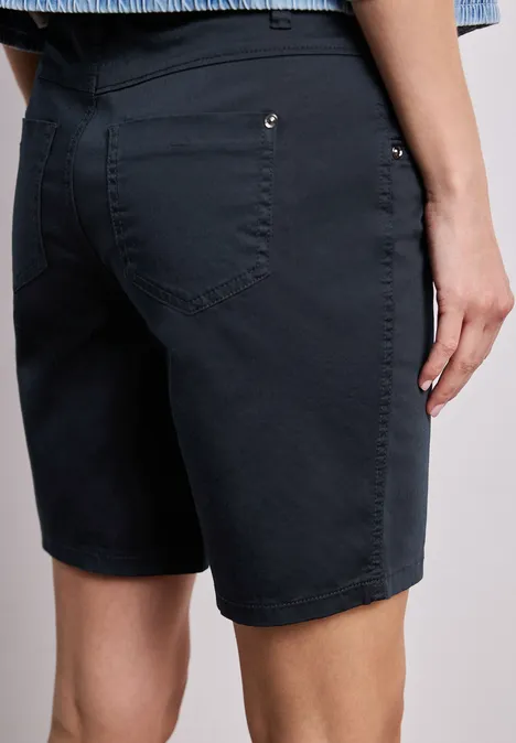 Rückansicht einer Person in dunkelblauen, knielangen Shorts.