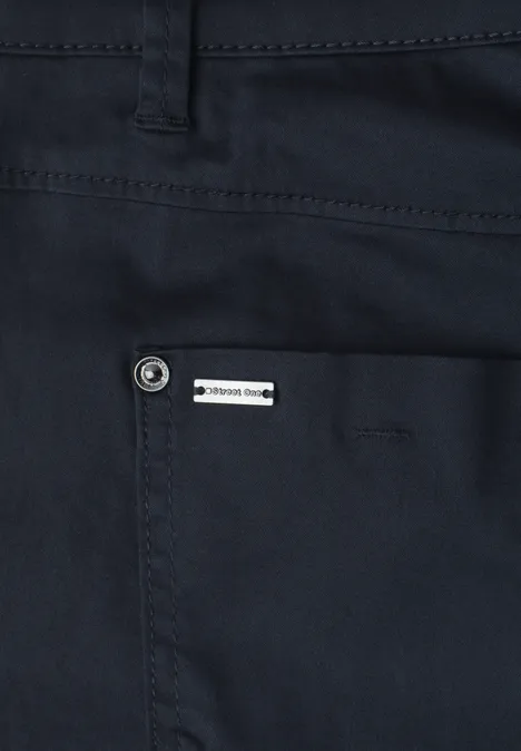 Nahaufnahme einer dunkelblauen Hose mit einer aufgesetzten Tasche und seitlichem Markenlabel.