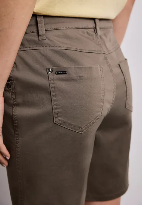 Rückenansicht einer Person in olivgrünen Shorts und hellem Oberteil.