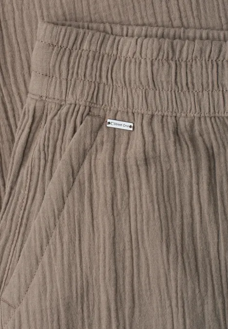 Close-up van taupekleurige, geribde katoenen broek met elastische taille en zijzak.