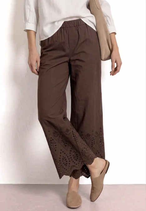 Braune Leinenhose mit weitem Bein und floraler Lochstickerei am Saum.