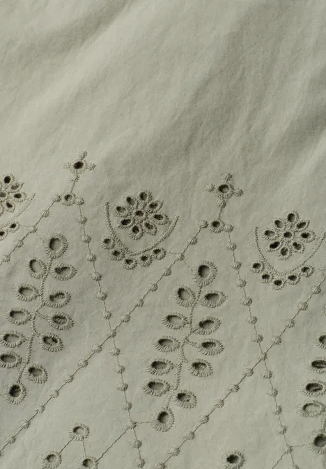 Licht linnen stof met fijne, symmetrische bloemen- en bladborduursels.