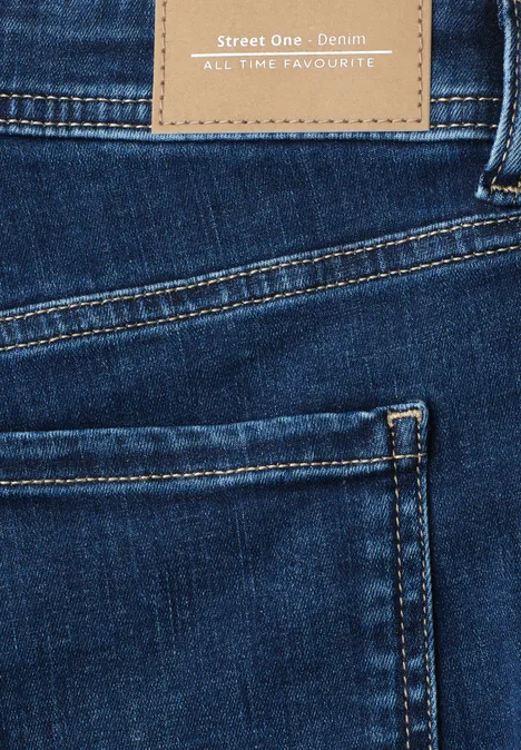 Close-up van een blauwe spijkerbroek met achterzak en bruin lederen label met "Street One Denim".