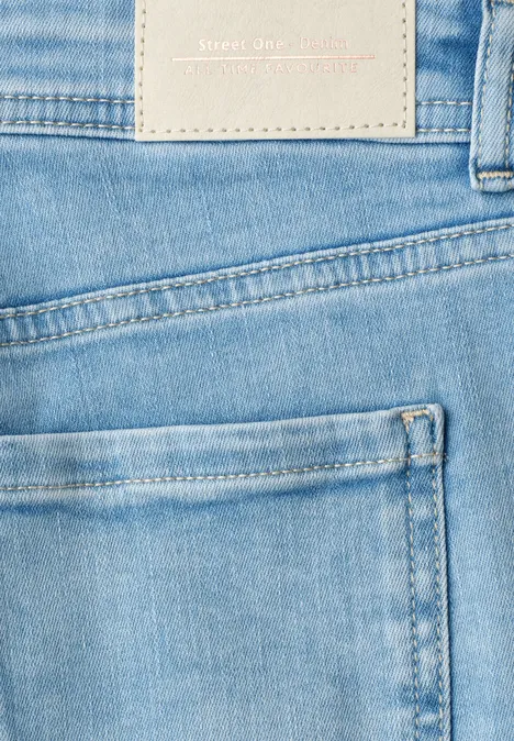 Close-up van een lichtblauwe spijkerbroek met achterzak en merklabel zichtbaar.