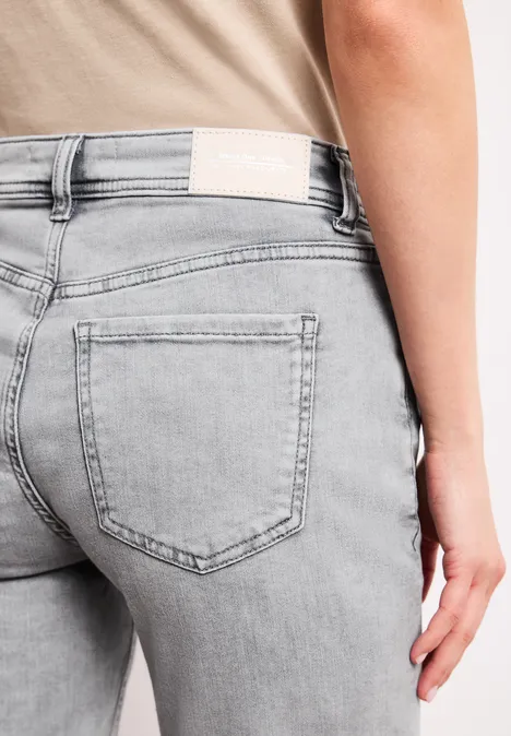 Bermuda met Slim Legs en omgeslagen detail mid grey wash Close-up van iemand in lichtgrijze, nauwsluitende spijkerbroek met achterzak.
