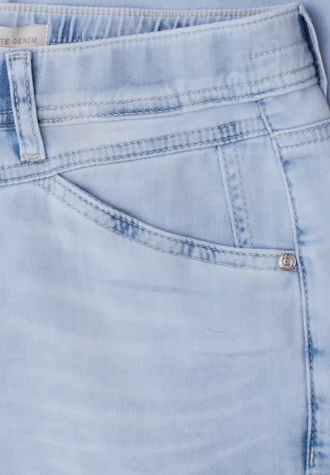 Lichtblauwe spijkerbroek, close-up van tailleband, zak en stiksels.