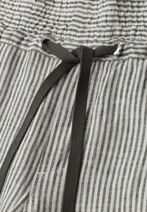 Nahaufnahme einer grauen Hose mit weißen Streifen und schwarzem Kordelzug am elastischen Bund