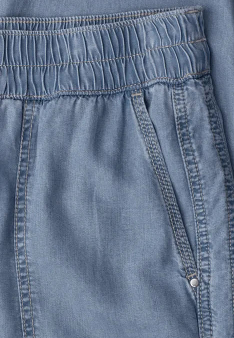 Lichtblauwe denimstof met elastische tailleband en zijzak.