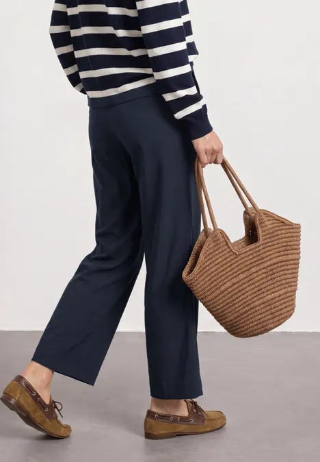 Straight Leg Hose mit Turn-Up-Detail deep blue Person trägt gestreiften Pullover, dunkelblaue Hosen, geflochtene Korbtasche und braune Plateau-Loafer.