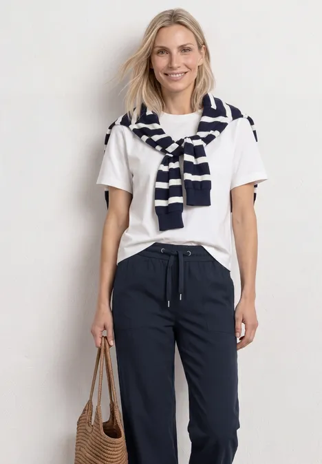 Straight Leg Hose mit Turn-Up-Detail deep blue Person trägt weißes T-Shirt, dunkelblaue Hose, gestreiften Pullover über den Schultern und hält eine braune Tasche.