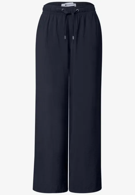 Schwarze, lockere, weite Hose mit elastischem Bund und Kordelzug, aus fließendem Material.