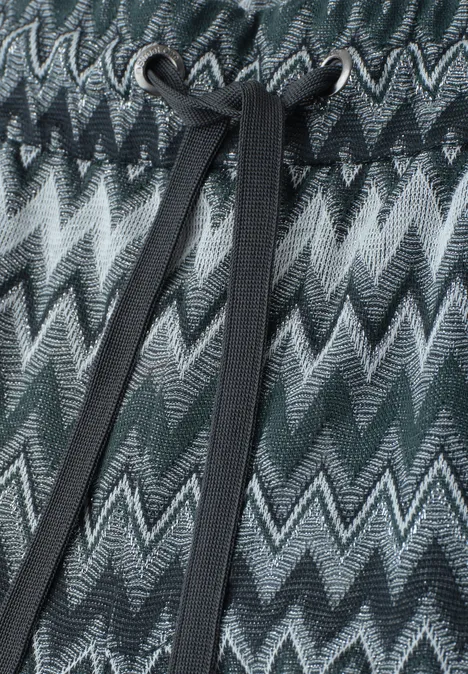 Gebreid zigzagpatroon in groen-, grijs- en zwarttinten met een zwarte koord centraal.
