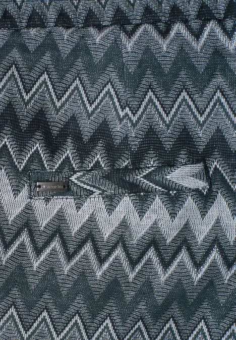 Wiederkehrendes Chevron-Muster in Grautönen mit abwechselnden Zickzacklinien auf Textilstruktur.