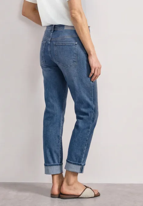 Straight Leg Jeans im Casual Fit mit Turn-Up Mid Blue Authentic washed Rückansicht einer Person in blauen, umgeschlagenen Straight-Leg-Jeans und flachen Sandalen, dazu weißes T-Shirt.