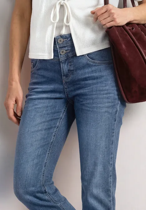 Straight Leg Jeans im Casual Fit mit Turn-Up Mid Blue Authentic washed Eine Person trägt blaue Jeans, ein weißes Oberteil und hält eine dunkelrote Tasche.