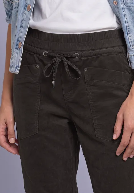 Slim Leg Cordhose im Loose Fit black coffee Nahaufnahme einer Person mit dunkelgrüner Cordhose, Tunnelzug und Jeansweste über weißem T-Shirt.