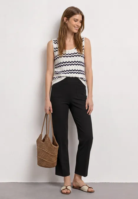 High Waist Straight Leg Hose im Casual Fit Black Frau trägt gestreiftes Top, schwarze Hose, Sandalen und Korbtasche.