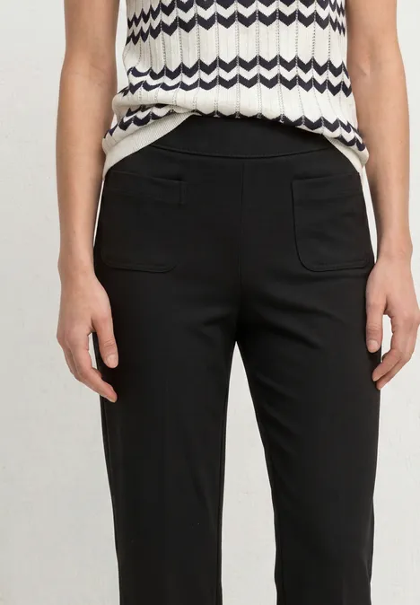 High Waist Straight Leg Hose im Casual Fit Black Schwarz-hose in schmaler Passform mit aufgesetzten Taschen kombiniert mit einem ärmellosen, gemusterten Top.