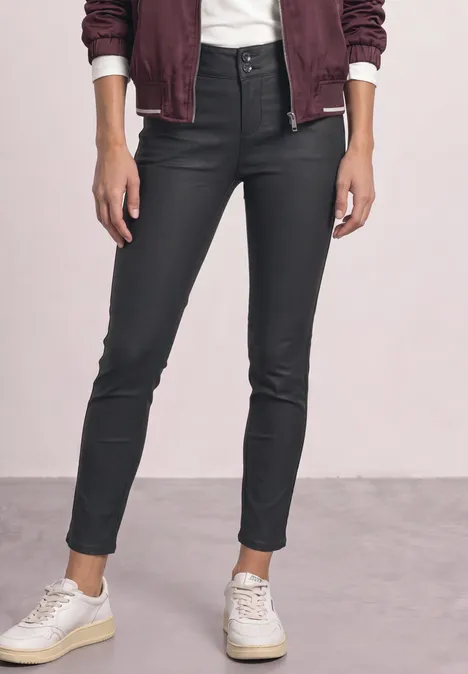 Pantalon taille mi-haute, coupe slim, aspect cuir Black Jeans noires moulantes enduites, taille haute, ourlets aux chevilles et baskets blanches.