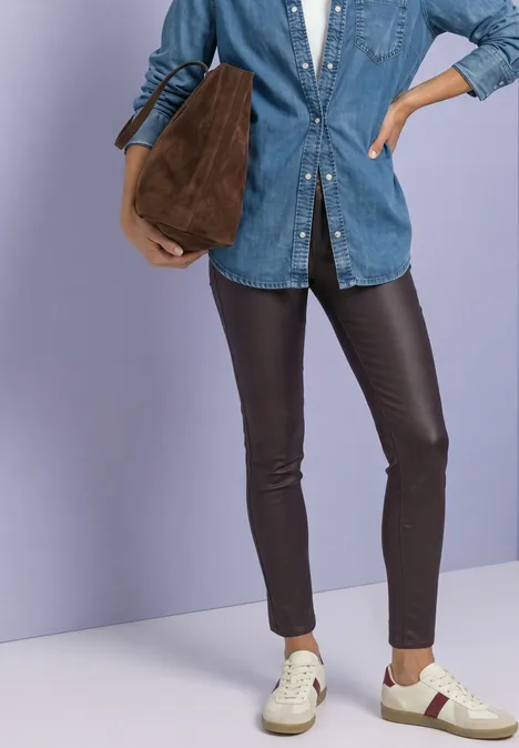 Pantalon taille moyenne, coupe slim, aspect cuir ruby vine Eine Person mit Jeanshemd, schwarzen Lederleggings, weißen Sneakern und einer braunen Tasche.