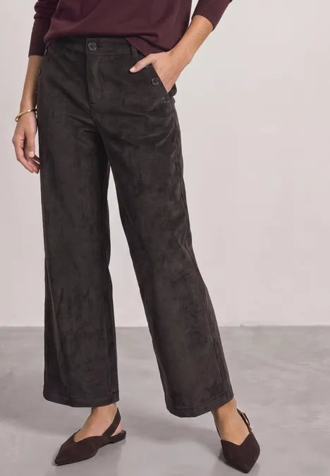 Dunkelbraune, weite Samthose mit seitlichen Taschen und flachen, spitzen Slingback-Schuhen.