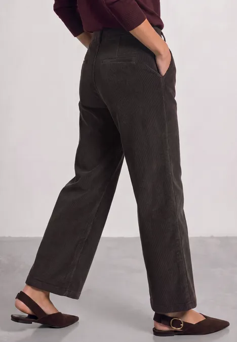 Dunkelbraune Cordhose mit weitem Schnitt und seitlichen Eingrifftaschen, kombiniert mit braunen Slippern.