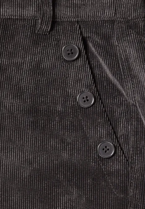 Detailaufnahme einer grauen Cordhose mit drei Knöpfen neben der Tasche.