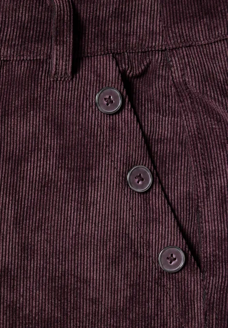 Bordeauxfarbener Cordstoff mit drei diagonalen Knöpfen neben einer Tasche