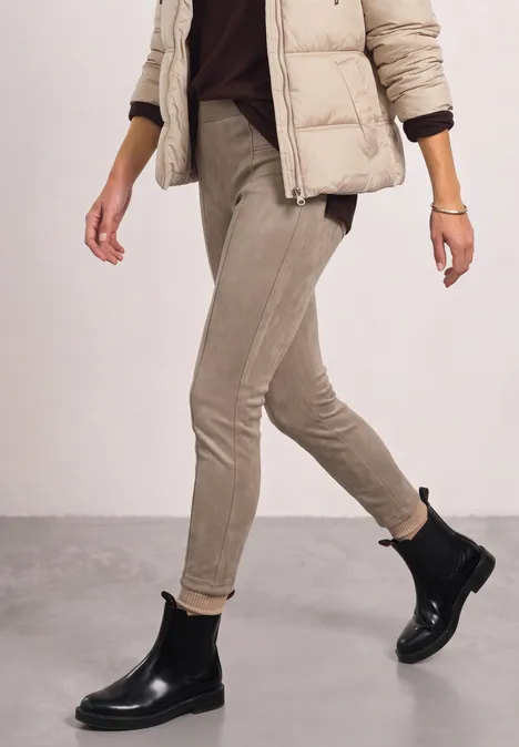Person geht in beiger Slim-Fit-Hose, Pufferjacke und schwarzen Chelsea-Boots.