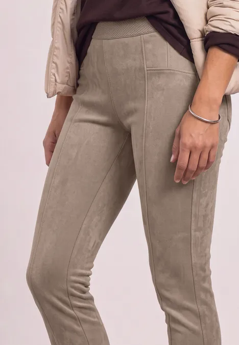 Naheinstellung einer Person in beigen Wildleder-Leggings und einer hellen Steppjacke