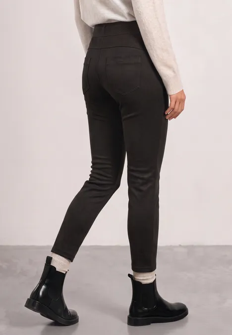 Rückansicht einer Person in schwarzen Skinny-Pants und schwarzen Stiefeletten mit weißem Futter.