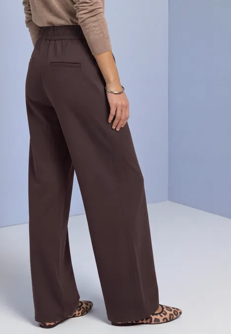 High Waist Straight Leg Hose im Casual Fit ruby vine Braune, weite Hose mit Leopardenmuster-Schuhen, seitliche Rückansicht vor hellblauem Hintergrund.