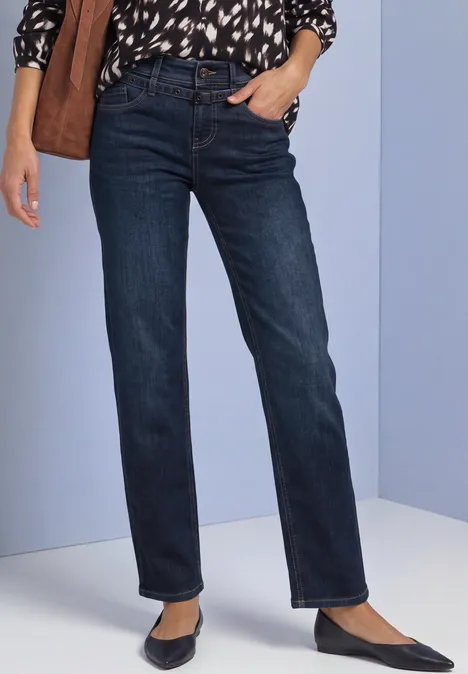 Frau trägt gerade geschnittene, dunkelblaue Jeans mit hohem Bund, seitlichen Taschen und spitzen schwarzen Ballerinas.
