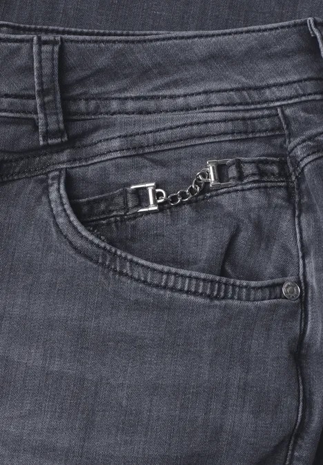 Dunkle Jeans mit sichtbaren Nähten und einer kleinen silbernen Kette an der vorderen Tasche.