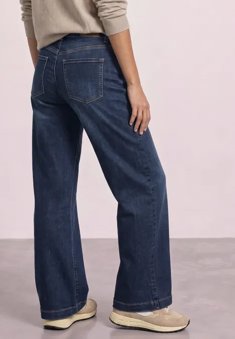 High Waist Wide Leg Jeans im Loose Fit Dark Blue Clean washed Rückansicht einer Person mit weitem, dunkelblauen Jeanshose und hellen Schuhen.