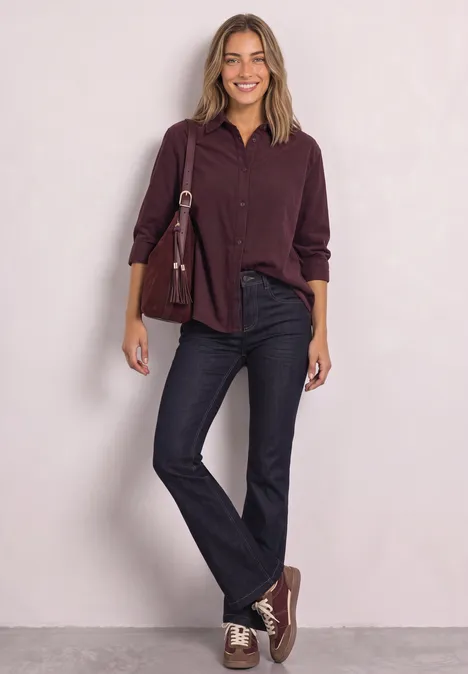 High Waist Bootcut Jeans im Slim Fit Rinse Soft Washed Eine Frau vor hellem Hintergrund trägt weinrotes Hemd, schwarze Jeans, passende Sneaker und eine Umhängetasche.